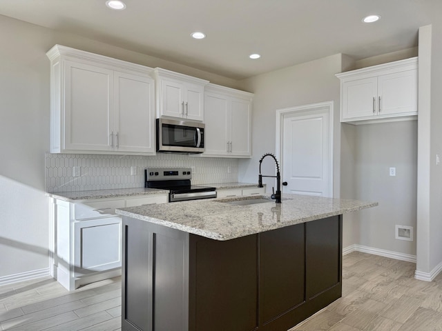 kitchen featuring white cabinets, appliances with stainless steel finishes, a center island with sink, and sink