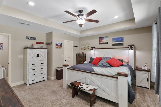 carpeted bedroom featuring a tray ceiling and ceiling fan