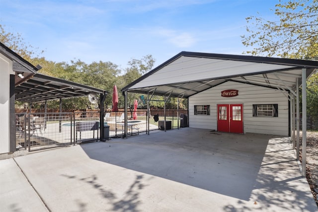 view of parking with a fenced in pool and french doors