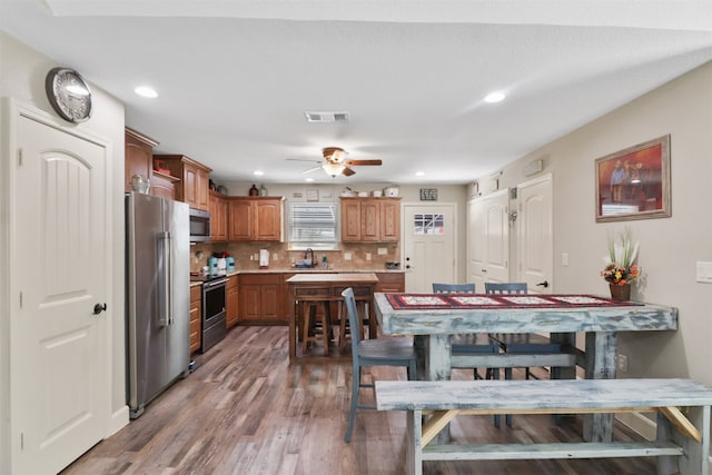 dining room featuring ceiling fan, sink, and wood-type flooring