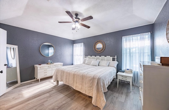 bedroom with light wood-type flooring, vaulted ceiling, multiple windows, and ceiling fan