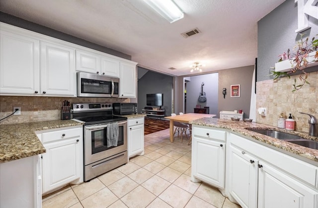 kitchen featuring white cabinets, appliances with stainless steel finishes, and tasteful backsplash