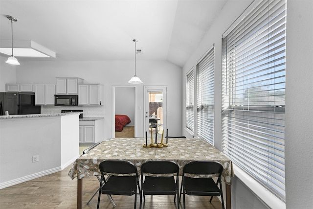 dining room with light wood-type flooring and vaulted ceiling