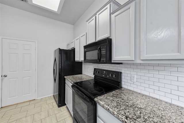 kitchen with light stone counters, a skylight, tasteful backsplash, white cabinetry, and black appliances