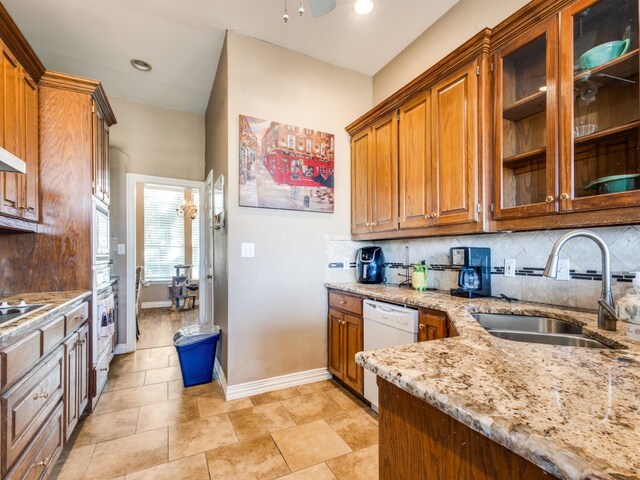 kitchen with backsplash, sink, light stone counters, and white dishwasher