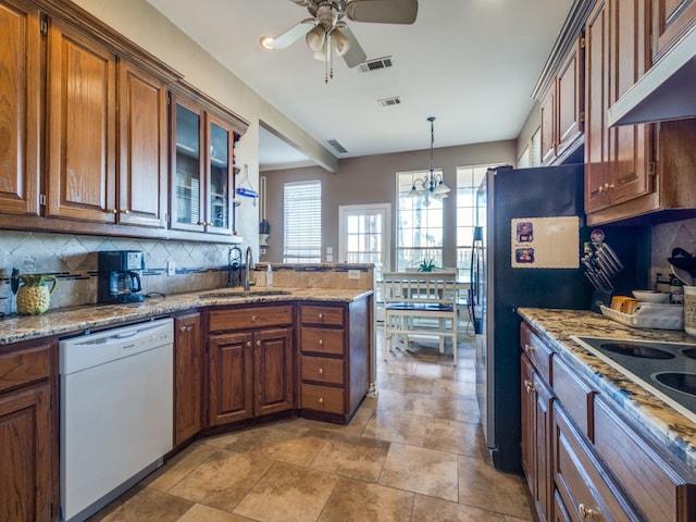 kitchen featuring light stone counters, sink, decorative light fixtures, backsplash, and black appliances