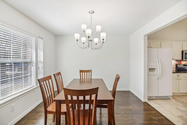 dining area with baseboards, a notable chandelier, and light wood-type flooring
