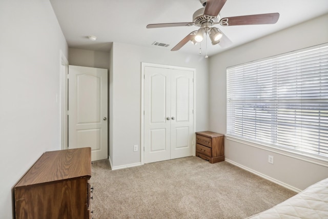 carpeted bedroom featuring ceiling fan and a closet