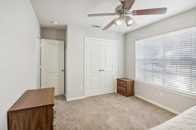 bedroom with a closet, a ceiling fan, light carpet, baseboards, and visible vents