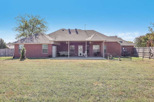 rear view of property with brick siding, a fenced backyard, a yard, and a patio area