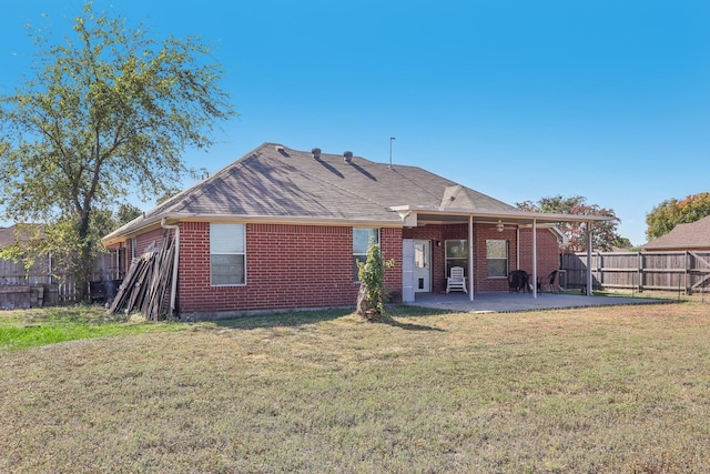 rear view of property featuring fence, a patio area, brick siding, and a yard