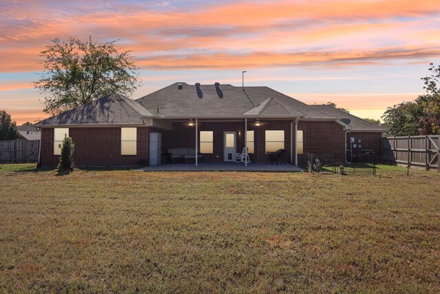 rear view of property featuring fence, a patio area, brick siding, and a yard