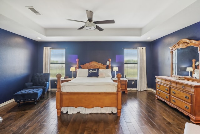 bedroom featuring ceiling fan, dark hardwood / wood-style flooring, and a raised ceiling