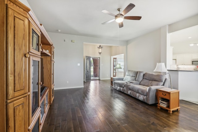 living room featuring baseboards, a ceiling fan, and dark wood finished floors