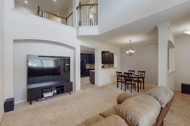 living room featuring crown molding, a towering ceiling, light carpet, and a notable chandelier