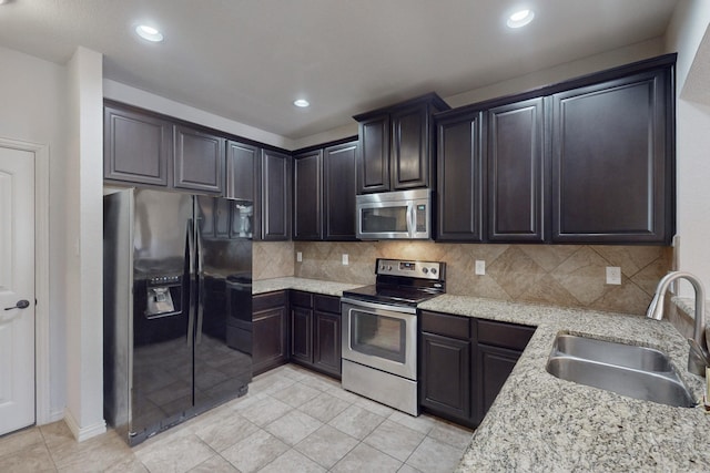 kitchen featuring appliances with stainless steel finishes, backsplash, light stone counters, and sink