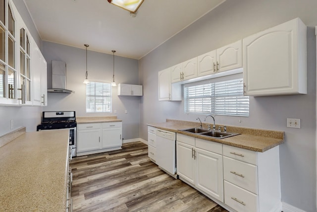 kitchen featuring wall chimney exhaust hood, sink, dishwasher, hanging light fixtures, and white cabinetry