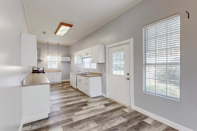 kitchen featuring stove, sink, light hardwood / wood-style floors, white cabinetry, and vaulted ceiling