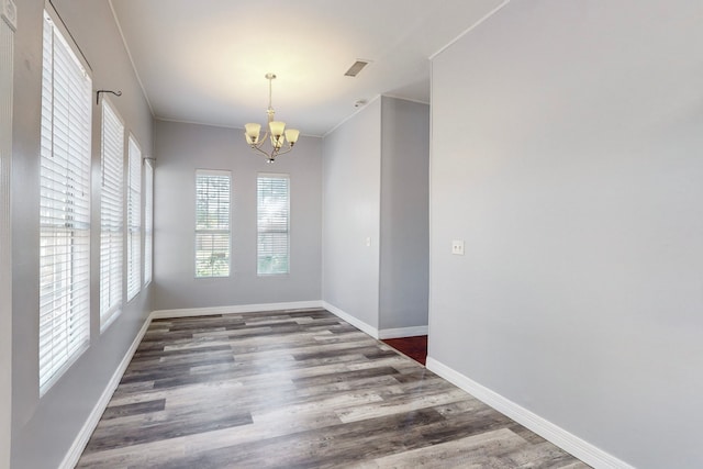 unfurnished dining area with ornamental molding, a chandelier, and dark hardwood / wood-style flooring