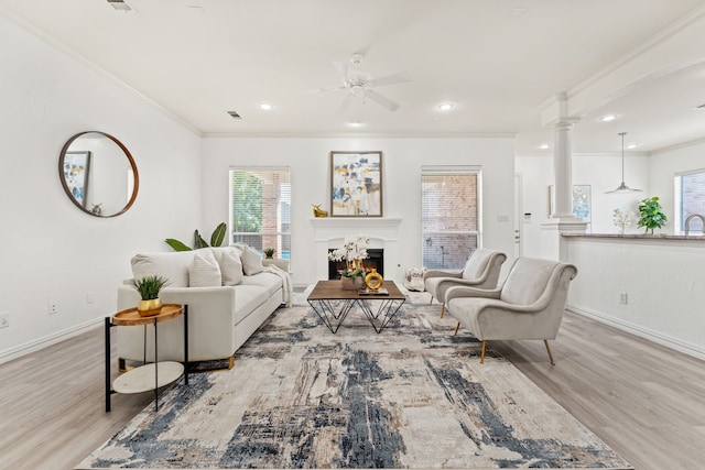 living room with light hardwood / wood-style floors, ornamental molding, and plenty of natural light