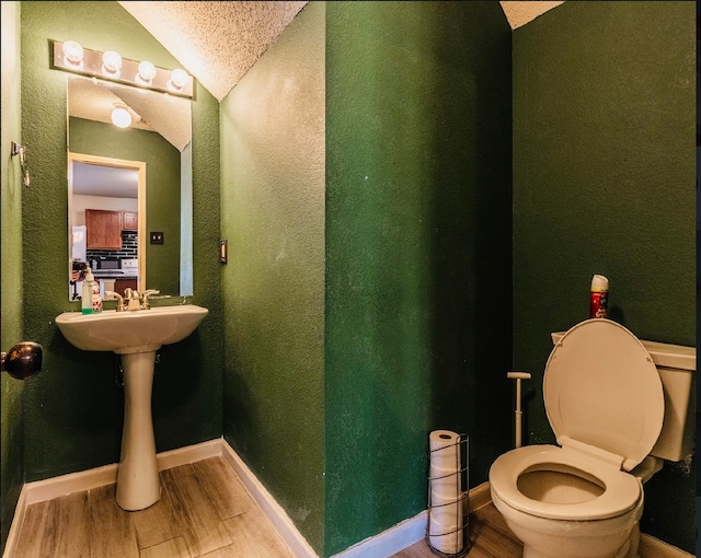 bathroom with toilet, a textured ceiling, hardwood / wood-style flooring, and vaulted ceiling