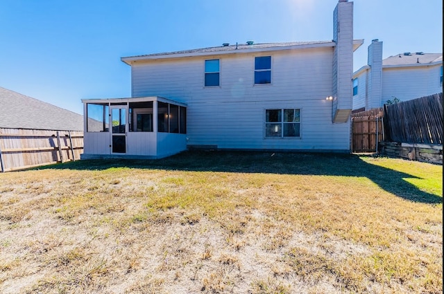 rear view of property with a yard and a sunroom