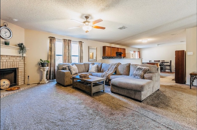 living room with a brick fireplace, a textured ceiling, light colored carpet, and ceiling fan