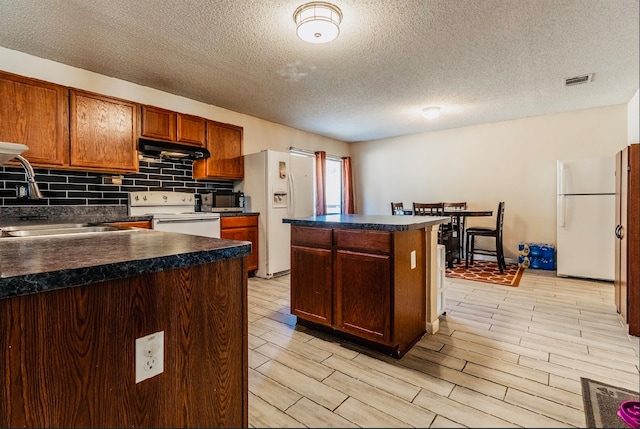 kitchen with a kitchen island, light hardwood / wood-style floors, a textured ceiling, and white appliances