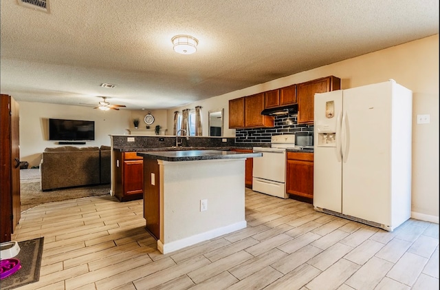 kitchen featuring light hardwood / wood-style floors, a center island, a textured ceiling, white appliances, and ceiling fan