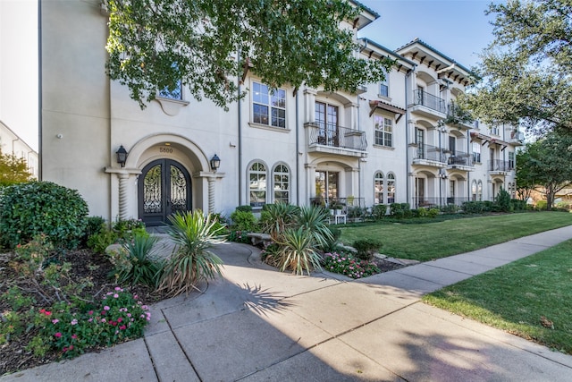 view of front of home with a front yard, french doors, and a balcony