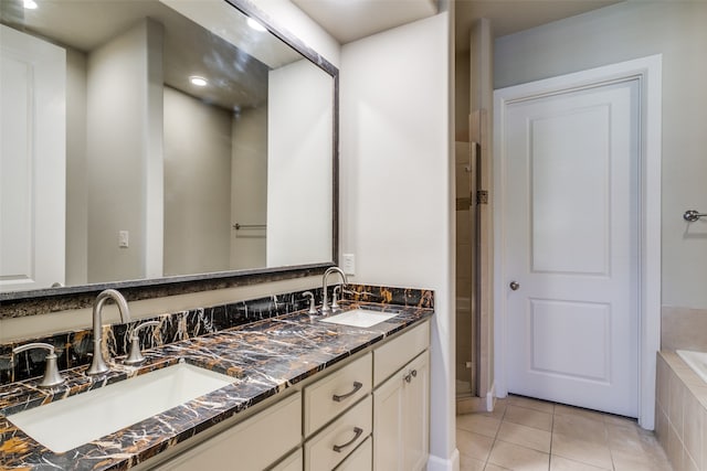 bathroom with tiled tub, vanity, and tile patterned floors