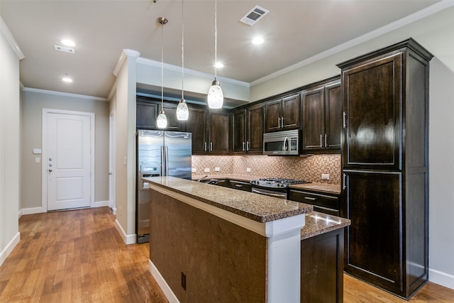 kitchen with pendant lighting, light hardwood / wood-style flooring, dark brown cabinets, appliances with stainless steel finishes, and a center island