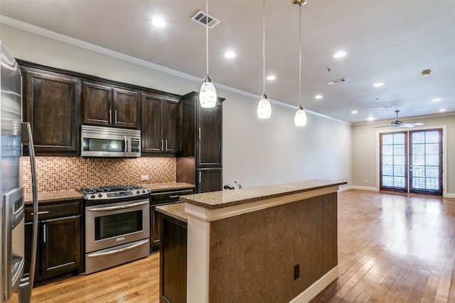 kitchen with pendant lighting, appliances with stainless steel finishes, light hardwood / wood-style floors, and a kitchen island