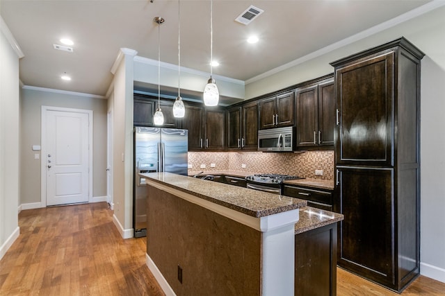 kitchen featuring a kitchen island, pendant lighting, backsplash, dark brown cabinetry, and stainless steel appliances