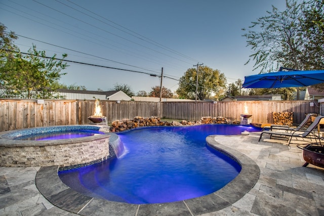 view of swimming pool with a patio area, pool water feature, and an in ground hot tub