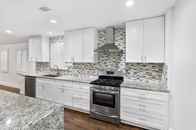 kitchen with white cabinets, backsplash, appliances with stainless steel finishes, dark hardwood / wood-style flooring, and wall chimney exhaust hood