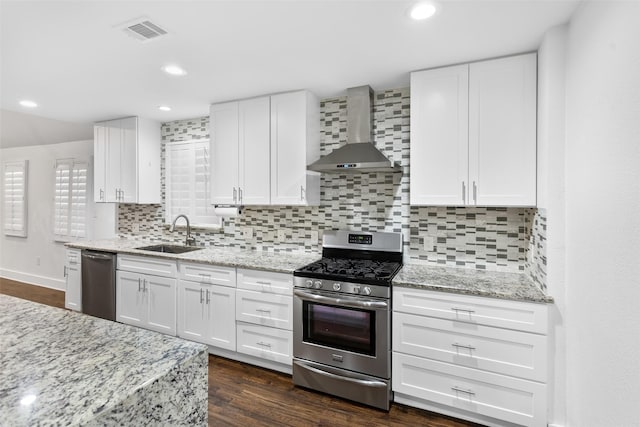 926 S Waverly Dr, Dallas, TX 75208 - kitchen featuring appliances with stainless steel finishes, wall chimney exhaust hood, a sink, white cabinets, and recessed lighting