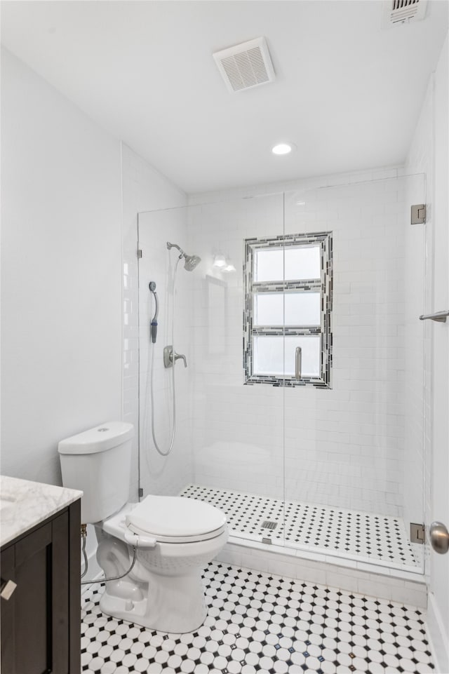 bathroom with vanity, toilet, a shower with shower door, and tile patterned flooring