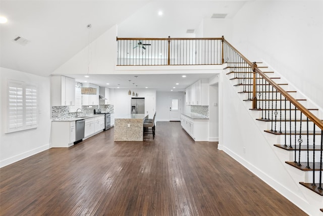 926 S Waverly Dr, Dallas, TX 75208 - kitchen featuring stainless steel appliances, a towering ceiling, a sink, dark wood-type flooring, and a kitchen bar