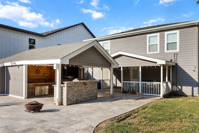 rear view of house with a patio area, exterior kitchen, a yard, and an outdoor fire pit