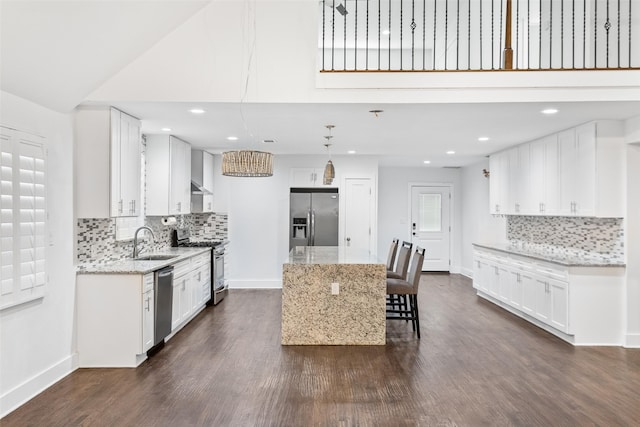 926 S Waverly Dr, Dallas, TX 75208 - kitchen with appliances with stainless steel finishes, a sink, a center island, light stone counters, and backsplash
