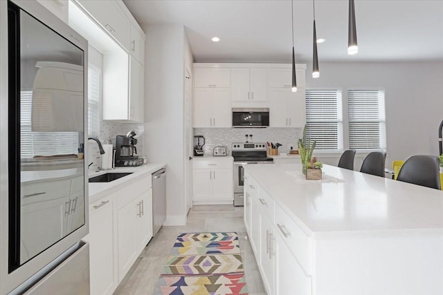 2604 Flora Ln, Denison, TX 75020 - kitchen with stainless steel appliances, a sink, backsplash, a center island, and light countertops