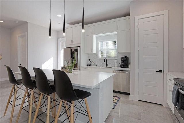2604 Flora Ln, Denison, TX 75020 - kitchen featuring appliances with stainless steel finishes, a sink, backsplash, a breakfast bar, and a center island