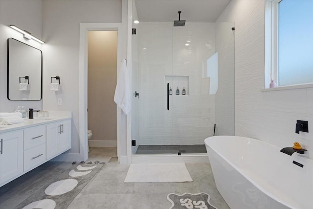 2604 Flora Ln, Denison, TX 75020 - bathroom featuring a shower stall, toilet, double vanity, and a freestanding bath