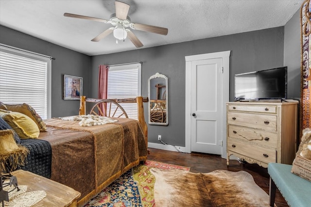 bedroom with dark wood-type flooring, ceiling fan, and a textured ceiling