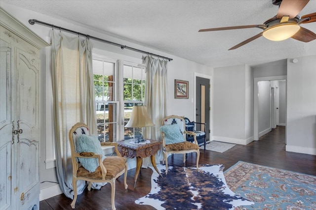 living area featuring ceiling fan, a textured ceiling, and dark hardwood / wood-style floors