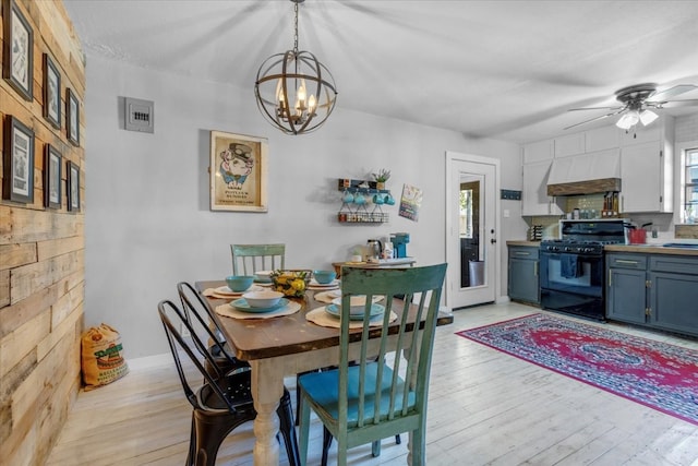 dining space featuring light wood-type flooring and ceiling fan with notable chandelier