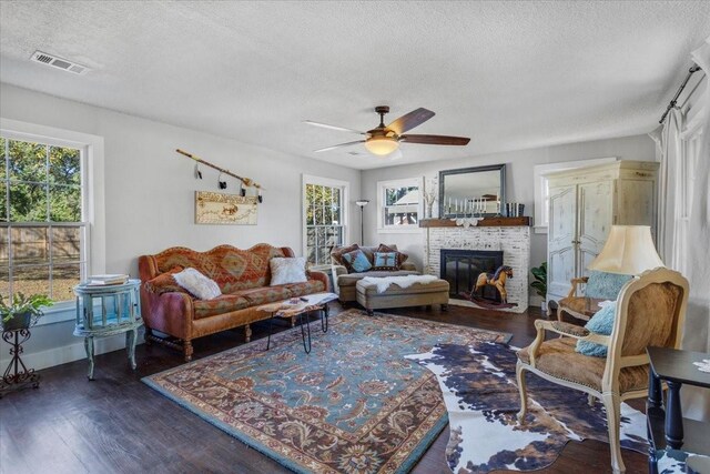 living room with dark wood-type flooring, a textured ceiling, and a healthy amount of sunlight