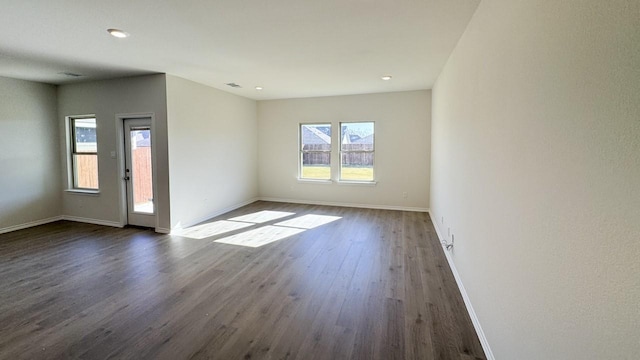 spare room featuring dark hardwood / wood-style flooring and a wealth of natural light