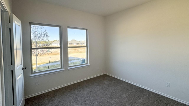 unfurnished room featuring dark carpet